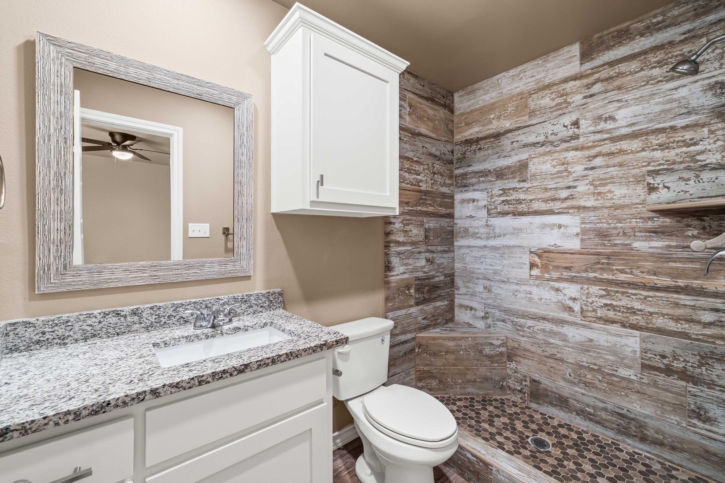 4202 East 64th Street Lubbock, TX 79403 - Photo 12 of 19 a bathroom with a granite countertop toilet and a sink
