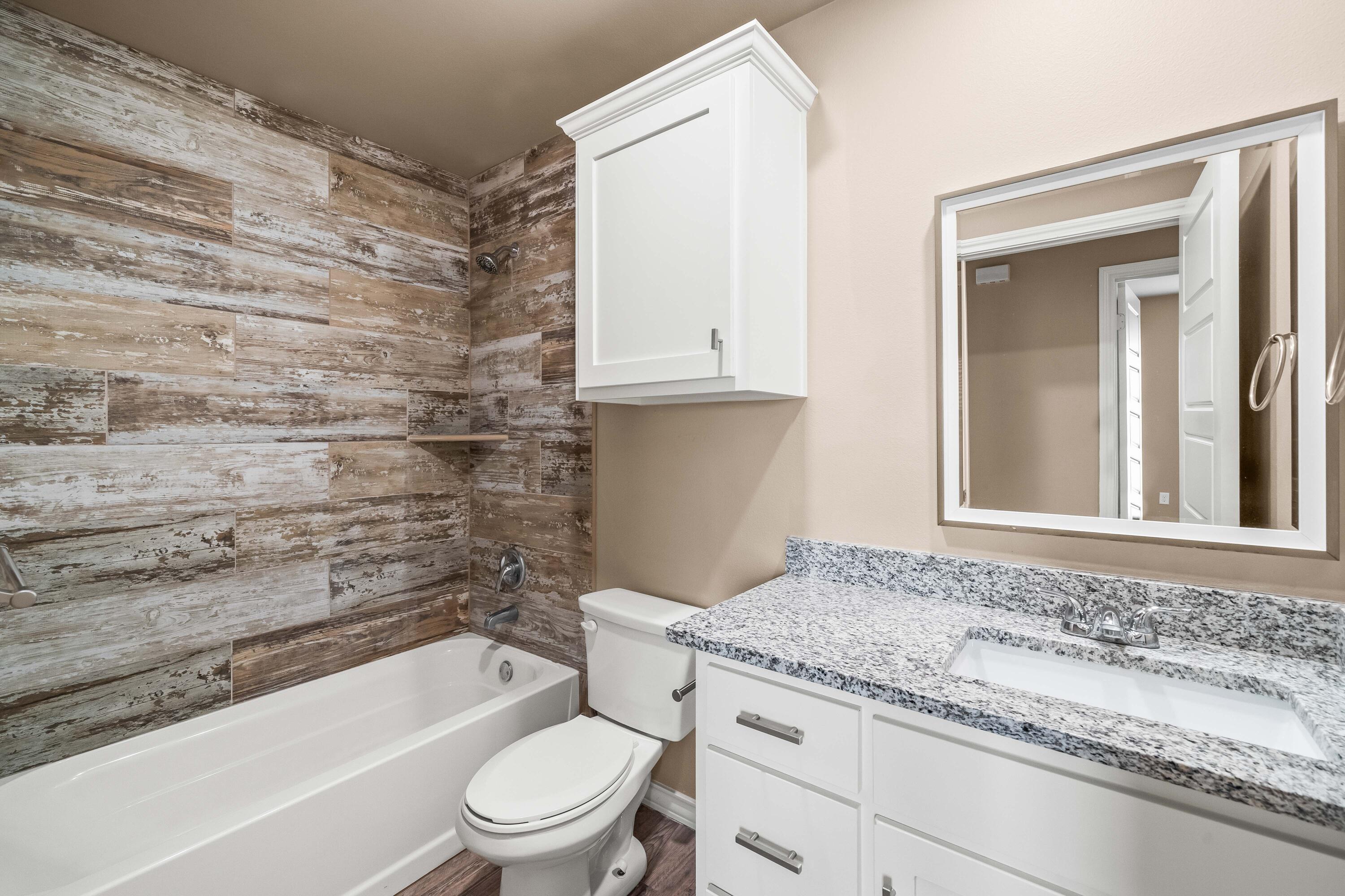 4202 East 64th Street Lubbock, TX 79403 - Photo 16 of 19 a bathroom with a granite countertop toilet a sink and bathtub