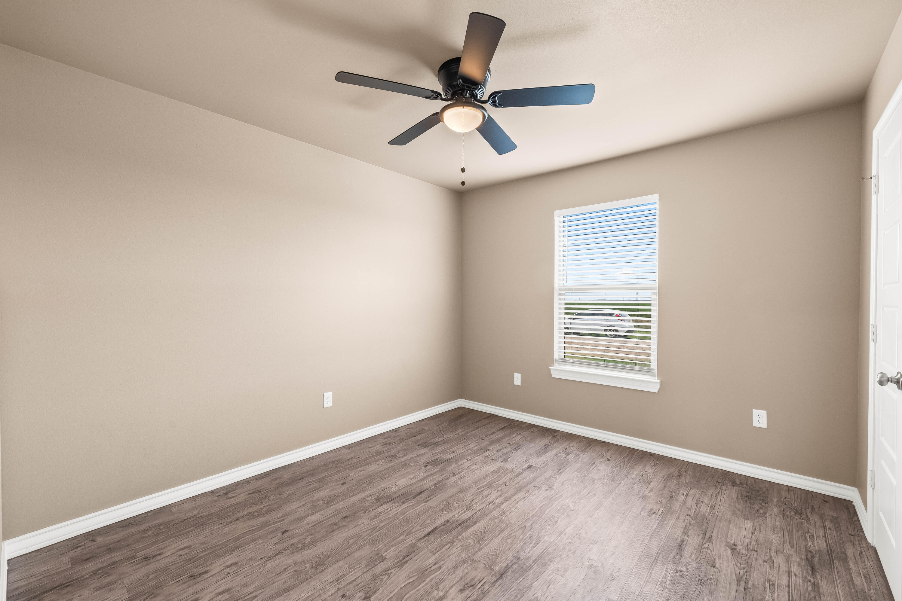 4202 East 64th Street Lubbock, TX 79403 - Photo 18 of 19 an empty room with wooden floor ceiling fan and windows