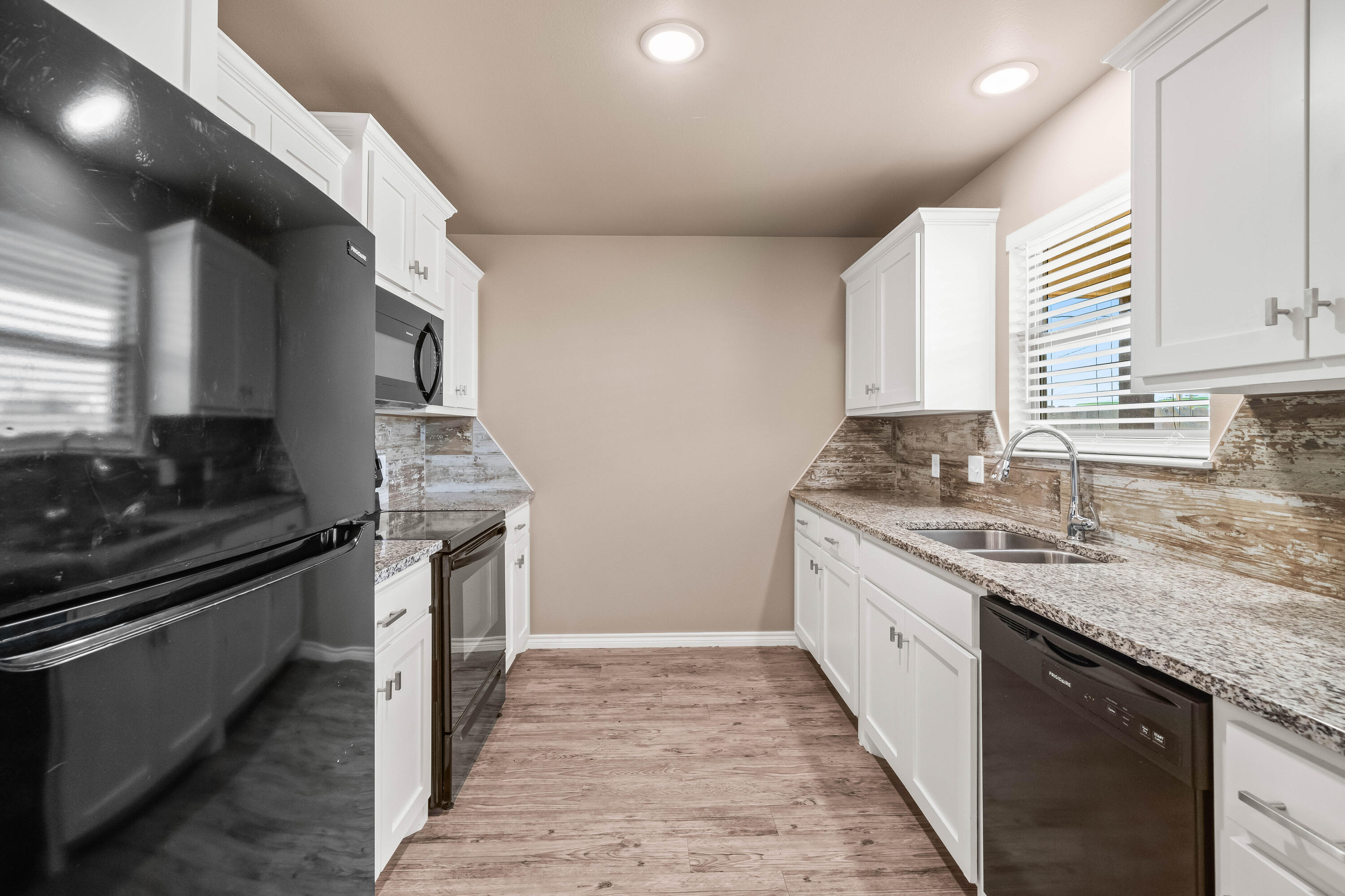 4202 East 64th Street Lubbock, TX 79403 - Photo 6 of 19 a kitchen with granite countertop sink stainless steel appliances and window