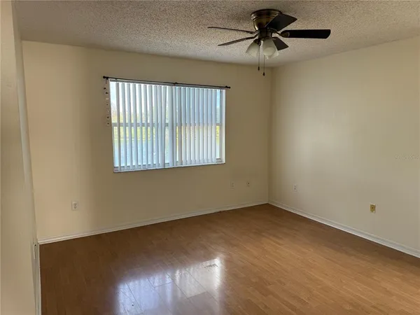 an empty room with a window and a ceiling fan