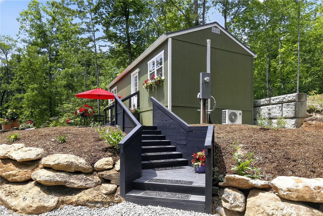 400 Mill Creek Road Sunset, SC 29685 - Photo 6 of 8 A private hillside retreat with a deep green exterior and a welcoming red umbrella-shaded patio awaits.