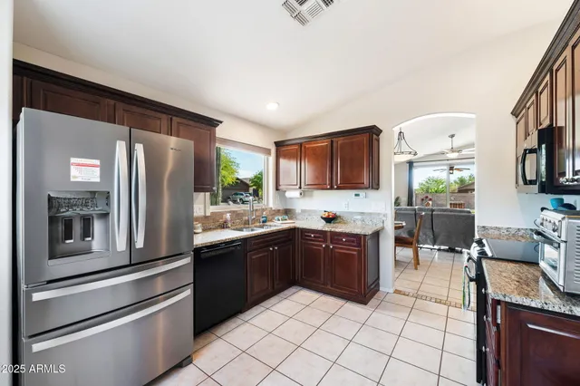 a kitchen with stainless steel appliances granite countertop a refrigerator and a stove top oven