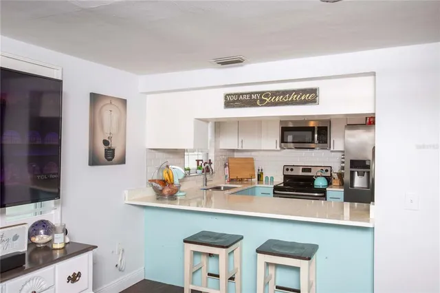 a kitchen with stainless steel appliances a sink a stove and white cabinets