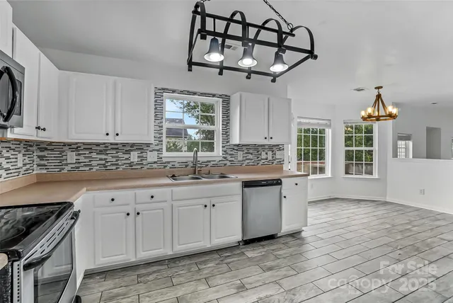 a kitchen with stainless steel appliances sink cabinets and window