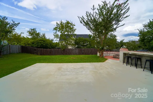 a view of a backyard with table and chairs and wooden fence