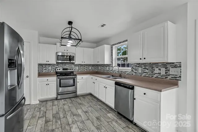 a kitchen with white cabinets stainless steel appliances and kitchen island