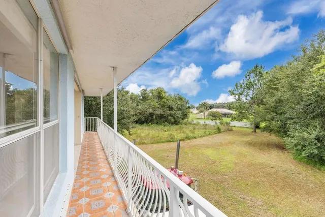 a white house with a small yard plants and large tree