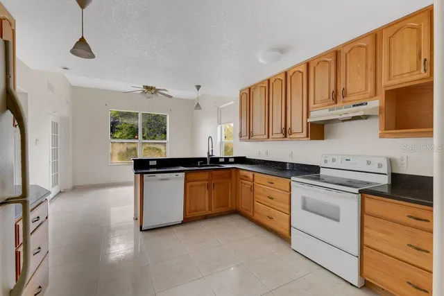 a kitchen with granite countertop white cabinets stainless steel appliances and a window