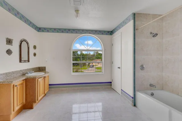 a bathroom with a granite countertop sink a large mirror and a bathtub