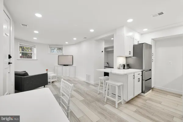 a large white kitchen with stainless steel appliances kitchen island granite countertop a refrigerator and cabinets