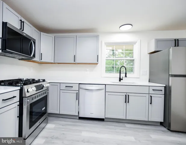 a kitchen with stainless steel appliances granite countertop a sink a stove a microwave and wooden cabinets