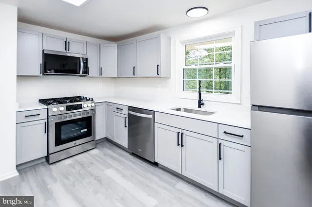 a kitchen with white cabinets appliances and window