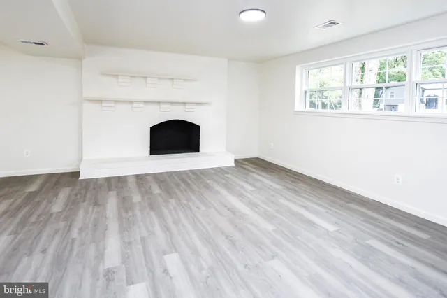 a view of an empty room with a fireplace and a window