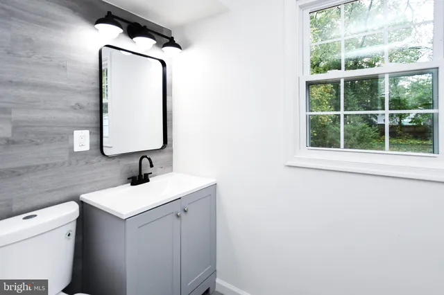 a bathroom with a toilet sink vanity and mirror