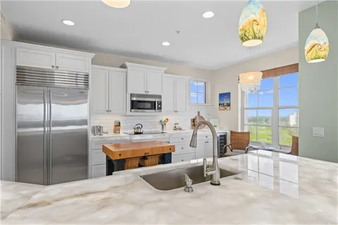 a kitchen with stainless steel appliances kitchen island granite countertop a refrigerator and a sink