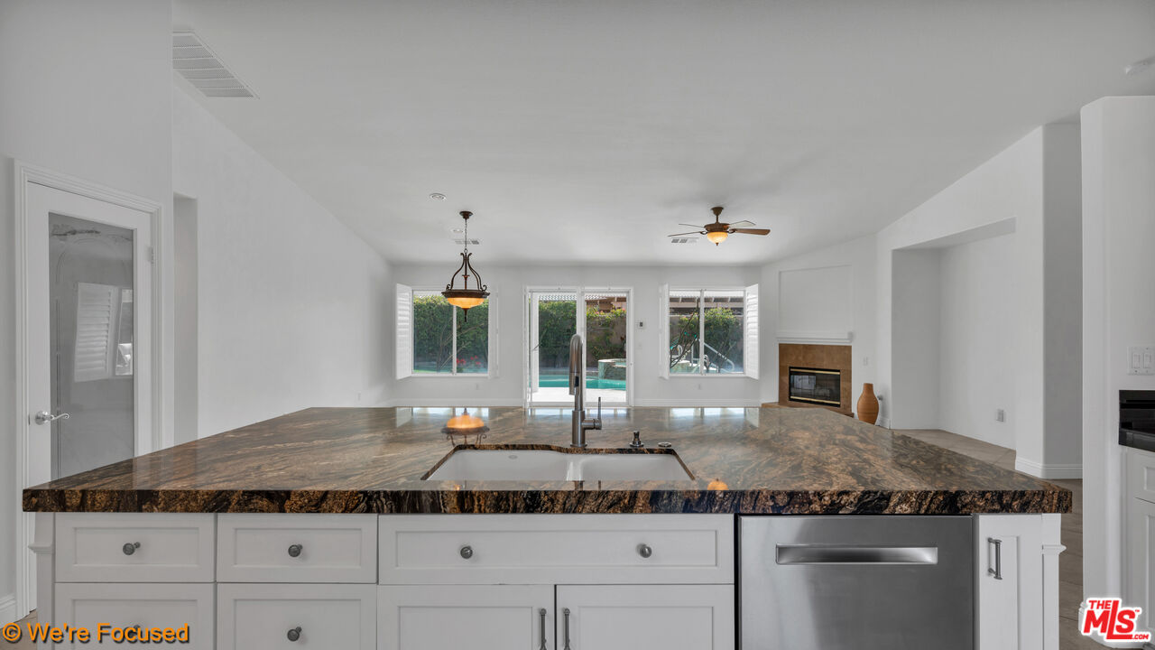 81129 La Reina Circle Indio, CA 92201 - Photo 13 of 46 a kitchen with kitchen island granite countertop a stove and white cabinets