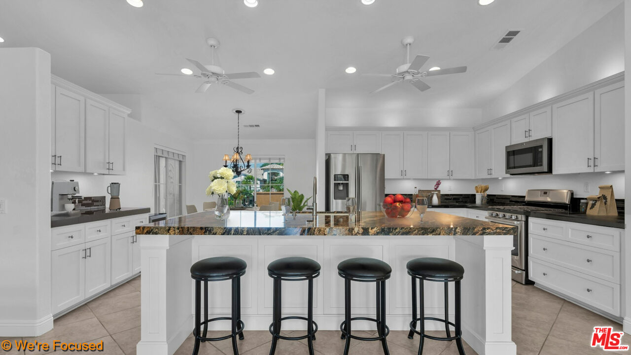 81129 La Reina Circle Indio, CA 92201 - Photo 6 of 46 a kitchen with granite countertop white cabinets and stainless steel appliances