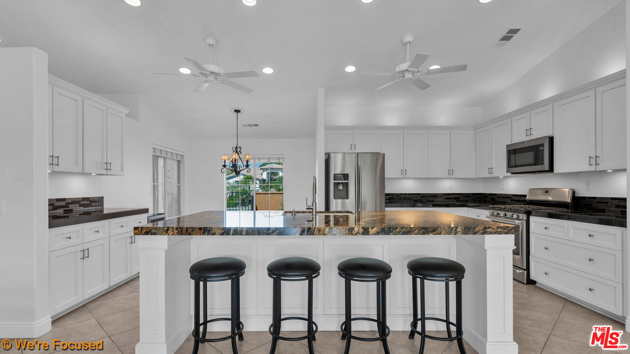 81129 La Reina Circle Indio, CA 92201 - Photo 7 of 46 a kitchen with granite countertop white cabinets and stainless steel appliances
