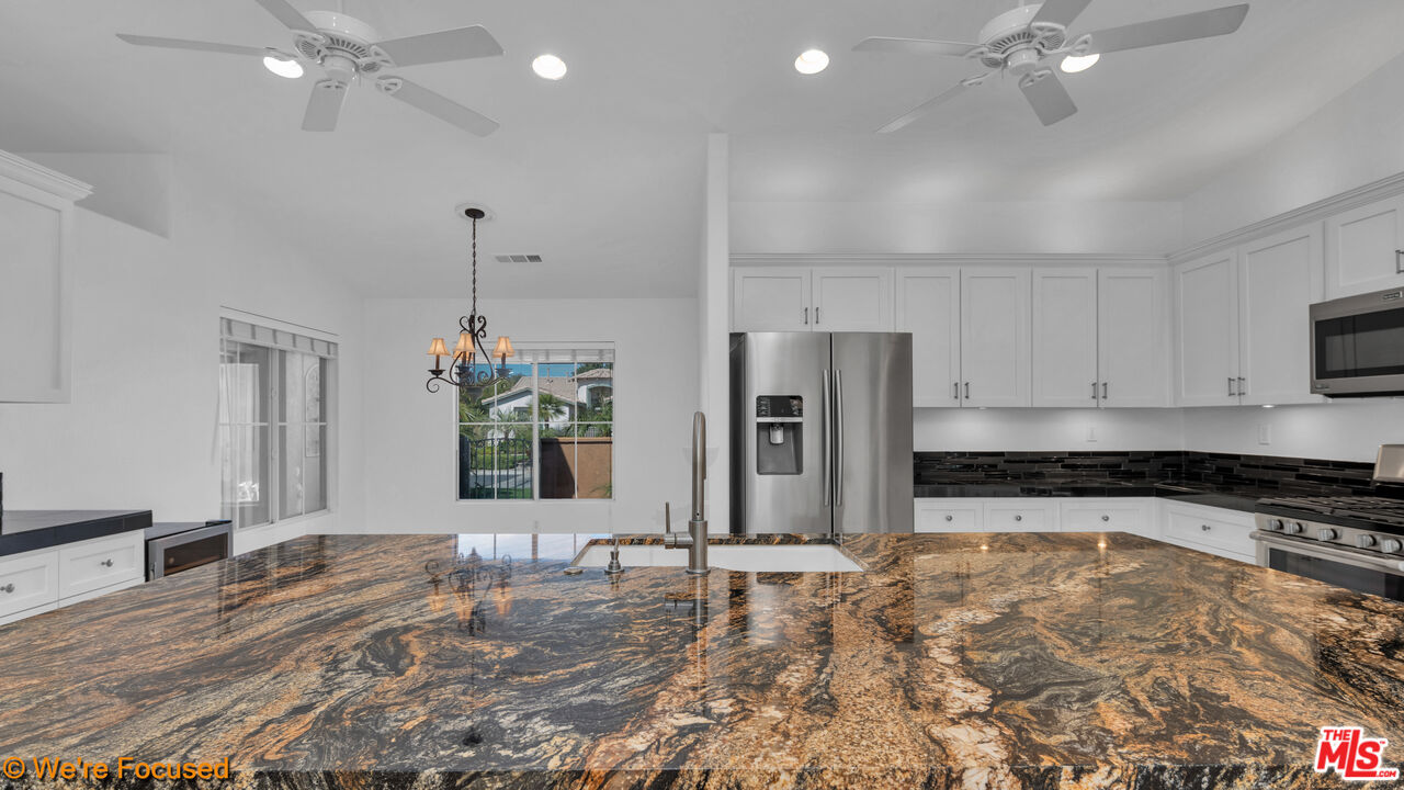 81129 La Reina Circle Indio, CA 92201 - Photo 9 of 46 a kitchen with stainless steel appliances kitchen island granite countertop a refrigerator and a sink