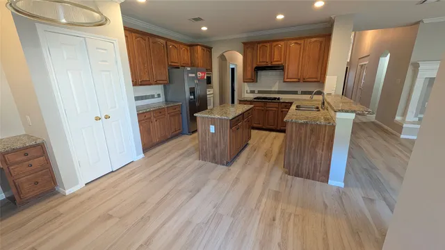 a kitchen with stainless steel appliances a refrigerator sink and wooden cabinets