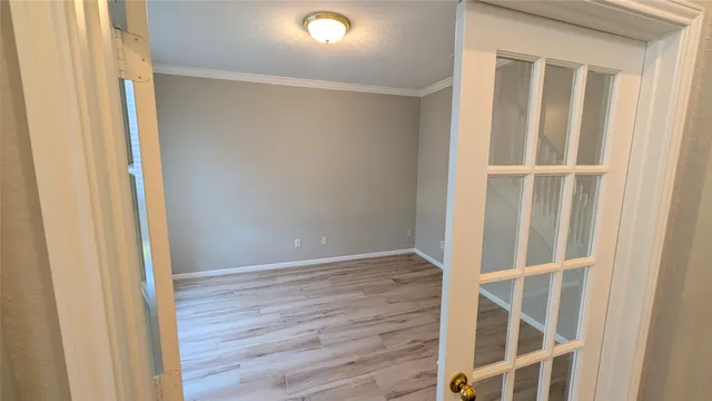 a view of an empty room with wooden floor and door
