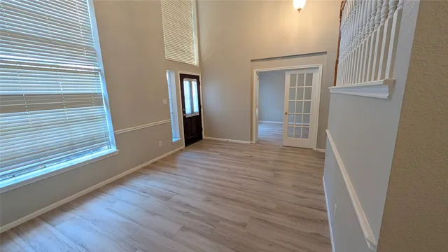 a view of an empty room with wooden floor and a window