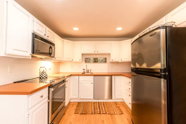 a kitchen with stainless steel appliances granite countertop a refrigerator sink and white cabinets