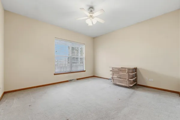 an empty room with windows and fan