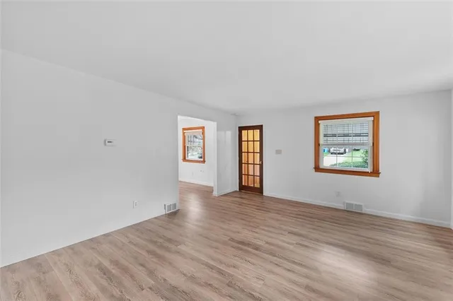 a view of an empty room with window and wooden floor