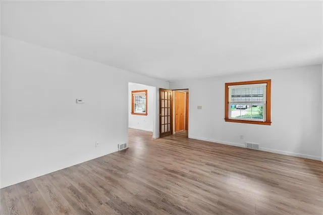 a view of an empty room with window and wooden floor