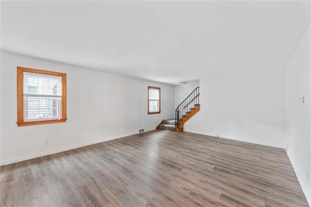 a view of an empty room with wooden floor and windows