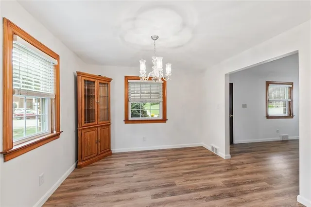 an empty room with wooden floor cabinet and windows