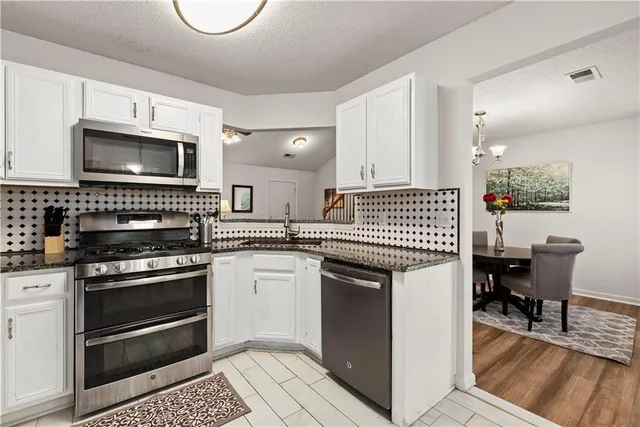 a kitchen with granite countertop a stove a sink and a microwave