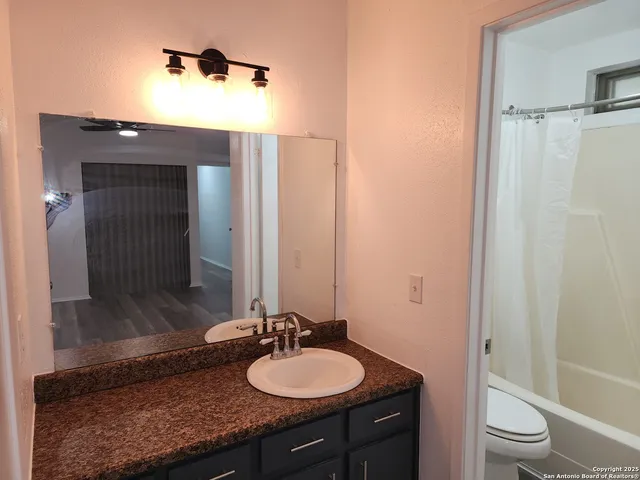 a bathroom with a granite countertop sink toilet mirror and shower