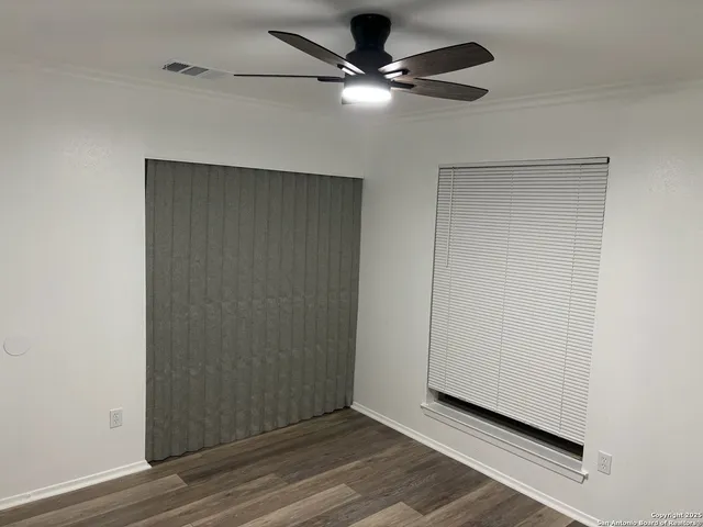 an empty room with a ceiling fan and wooden floor