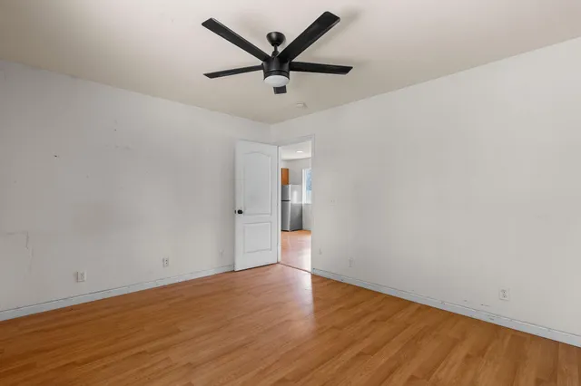 an empty room with wooden floor and ceiling fan