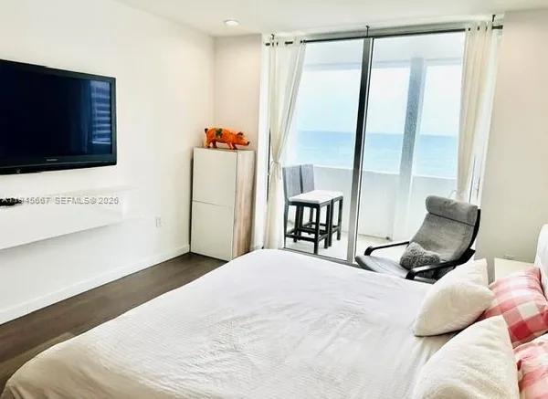 a bedroom with a bed a flat screen tv and next to a window