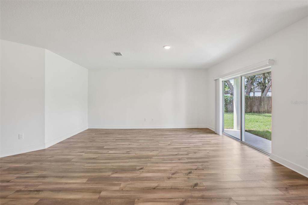 3033 Magellan Avenue Spring Hill, FL 34608 - Photo 12 of 42 a view of an empty room with wooden floor and a window