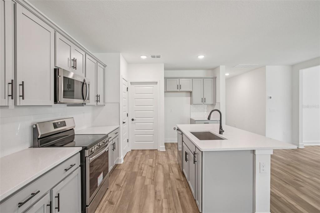 3033 Magellan Avenue Spring Hill, FL 34608 - Photo 22 of 42 a kitchen with stainless steel appliances granite countertop a sink stove and refrigerator