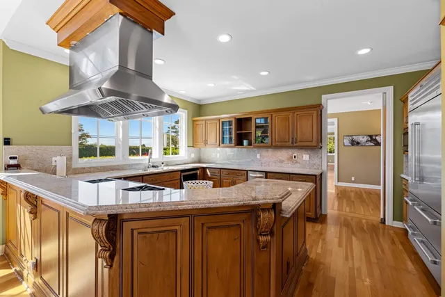 a kitchen with stainless steel appliances granite countertop a sink a stove and a wooden floors