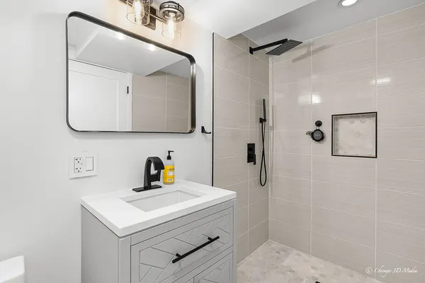 a bathroom with a sink a mirror a vanity and shower