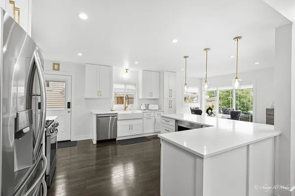 a large kitchen with sink a refrigerator and wooden floor