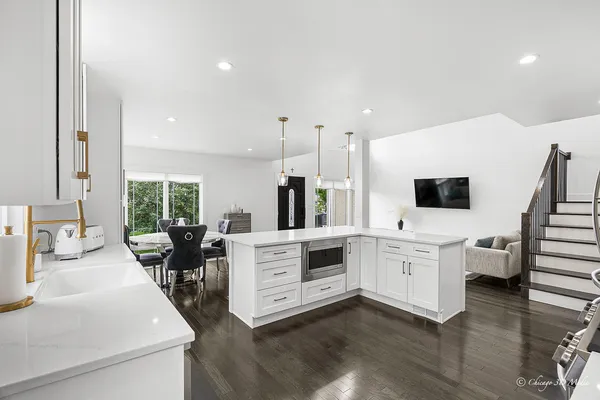 a large white kitchen with sink stove and chairs