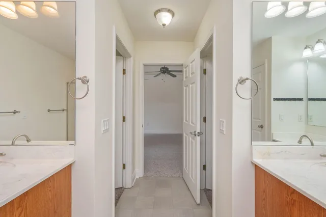 a bathroom with a granite countertop sink two mirror and shower