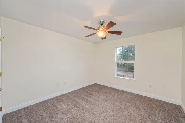 an empty room with a window and ceiling fan