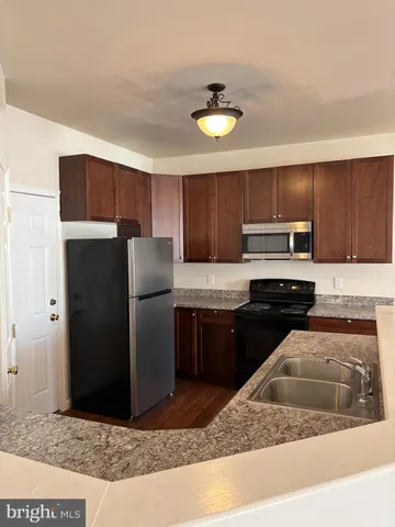 a kitchen with stainless steel appliances granite countertop a refrigerator a stove a sink and dishwasher