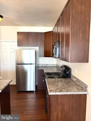a kitchen with granite countertop a refrigerator and a stove top oven