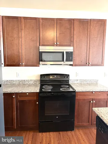 a stove top oven sitting inside of a kitchen with granite countertop wooden cabinets