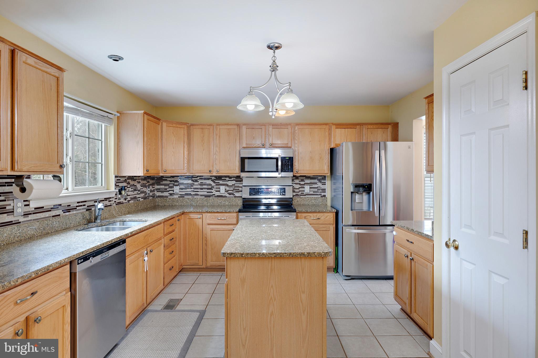 8008 Carlean Court Pasadena, MD 21122 - Photo 8 of 35 a kitchen with granite countertop stainless steel appliances a refrigerator stove top oven and sink